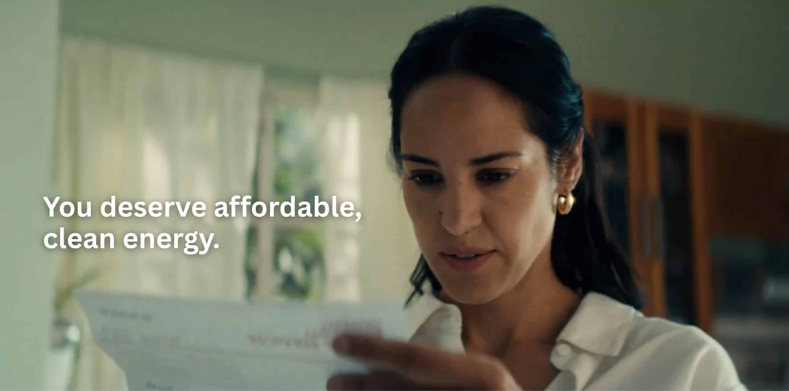 Photo of woman looking at utility bill with "You deserve affordable, clean energy"