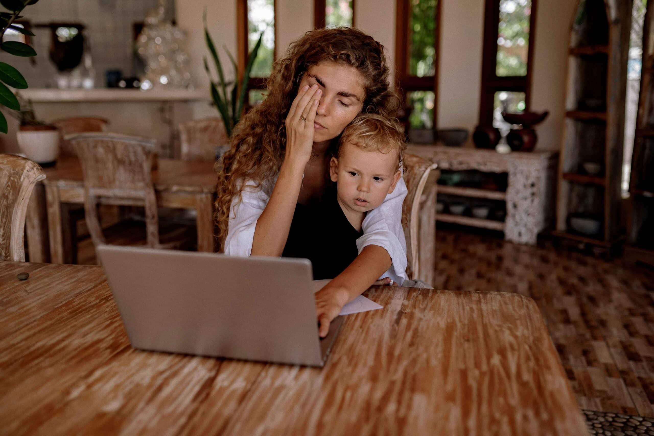 Woman doing bills at kitchen table with child